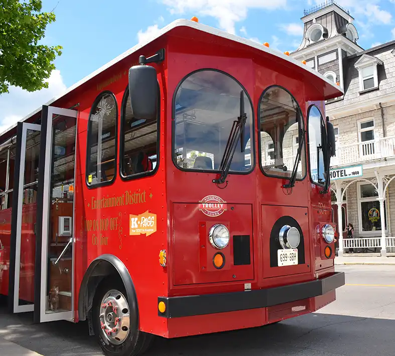 Red Trolley parked at the front of the Visitors information centre in Kingston, Ontario. Across from the Prince George Hotel, a limestone, 3 storey building.