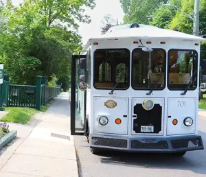 Front view of the white wedding trolley with it's front door open, on a bright sunny day. Parked outside of Bellevue House.